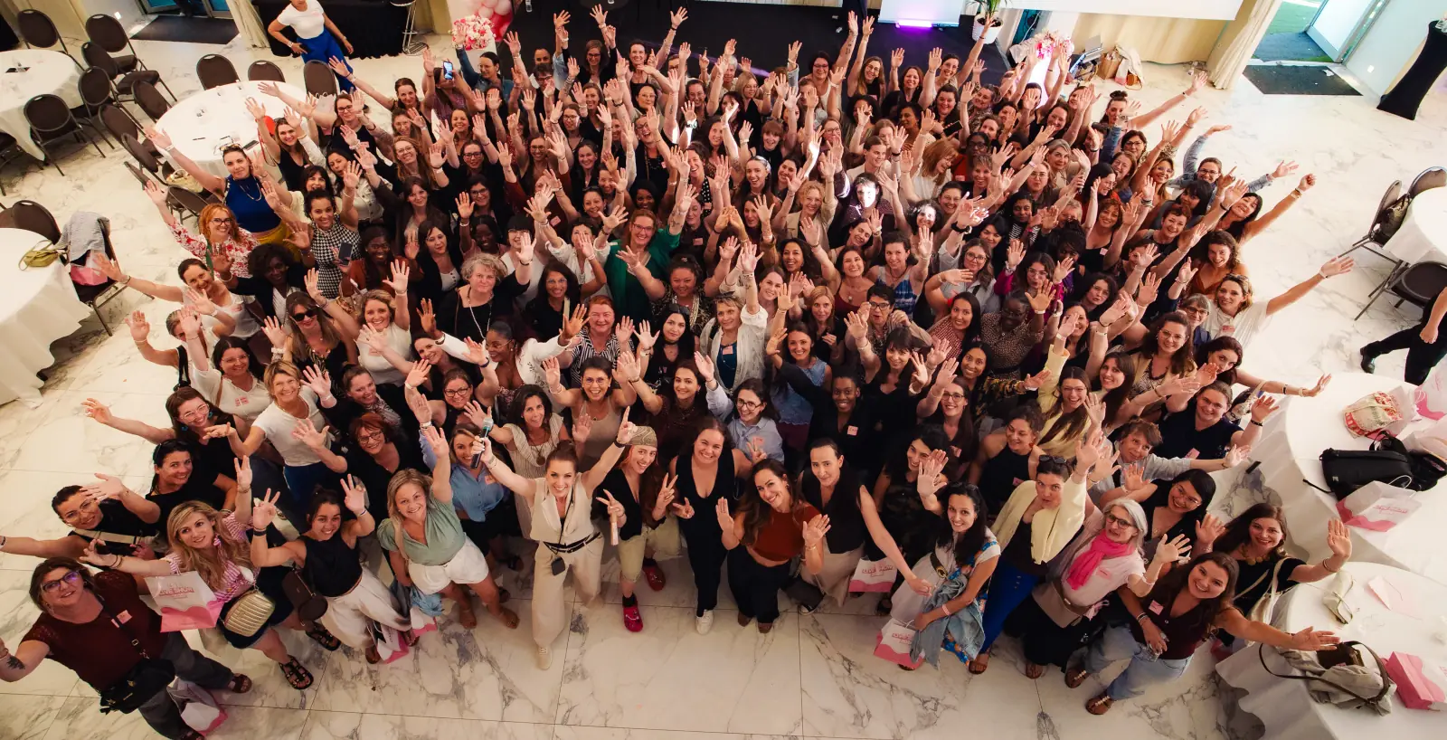 Des centaines d'entrepreneuses, bras levés, réunies dans une salle au Live Show d'Entrepreneuses Académie